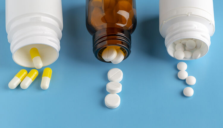 Various pills bottles and heap of drugs on blue backround